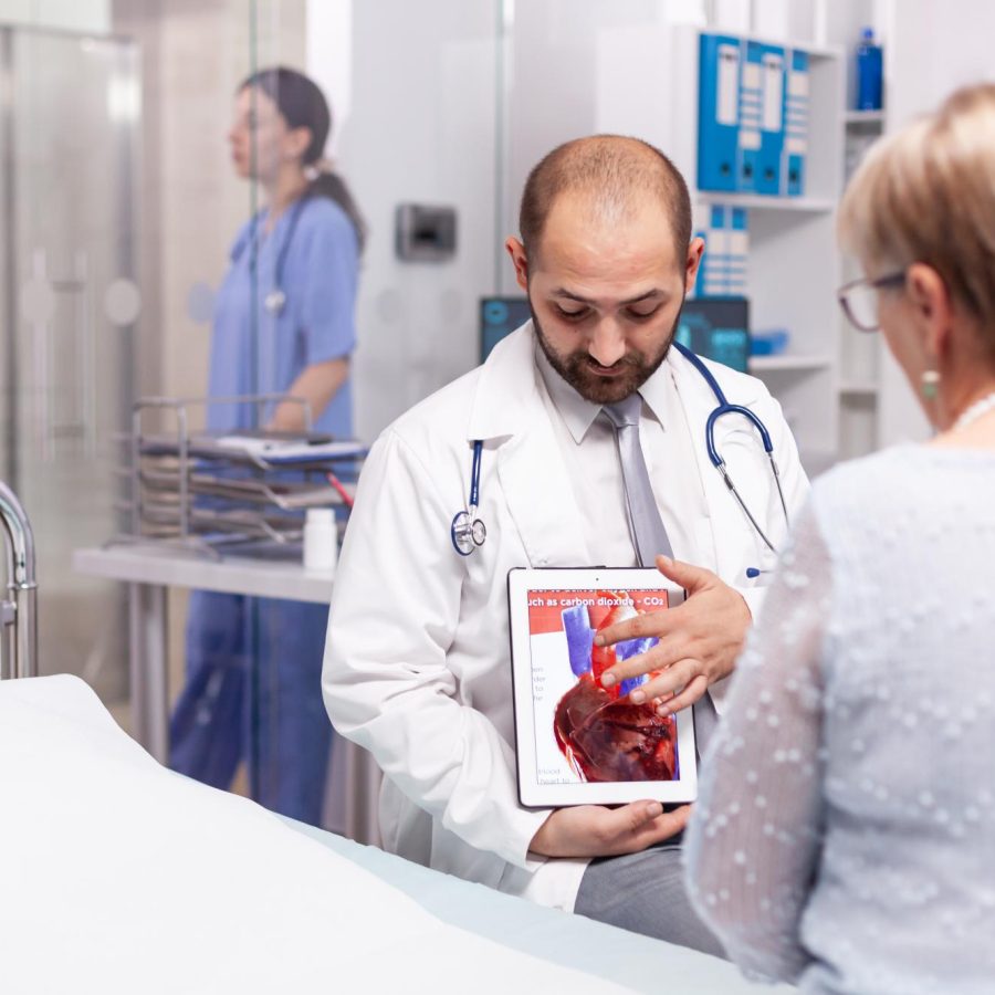 doctor-talking-about-efect-heart-attack-pointing-tablet-pc-during-senior-woman-examination(1)